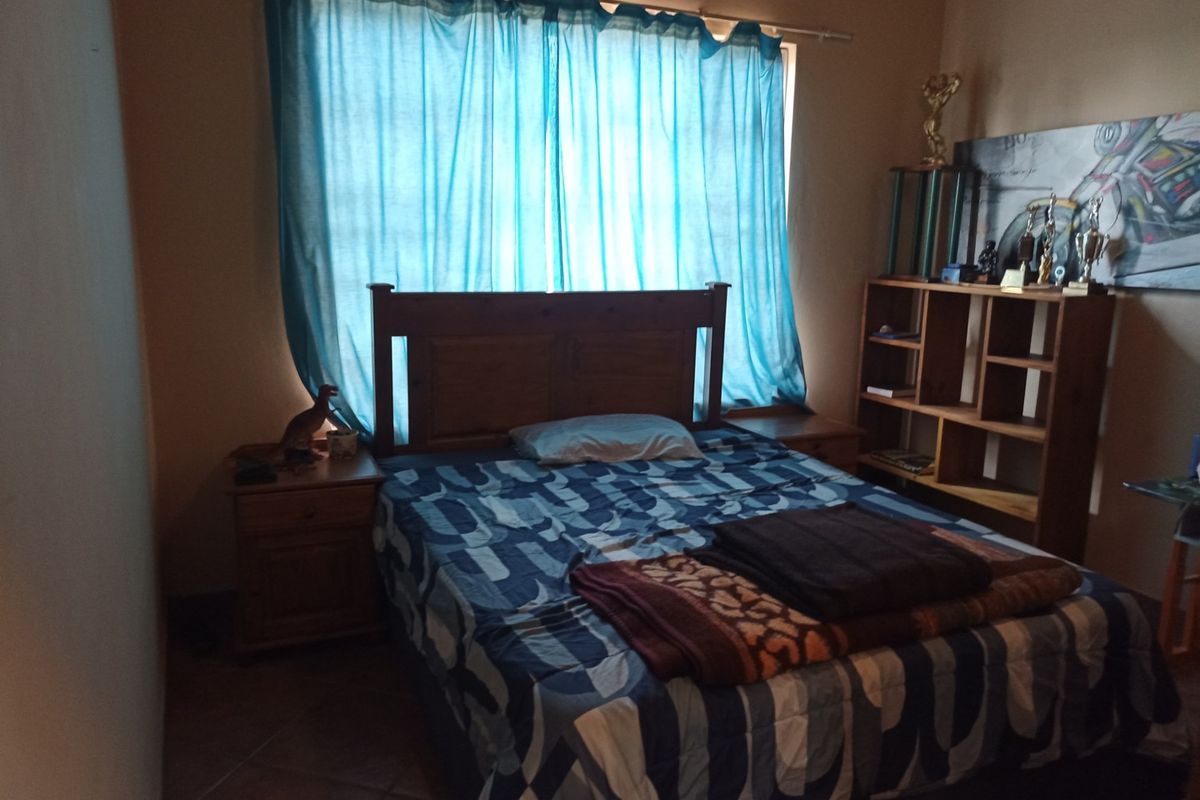A standard bedroom featuring tiled flooring and a window with a curtain rod, providing a functional space for rest.