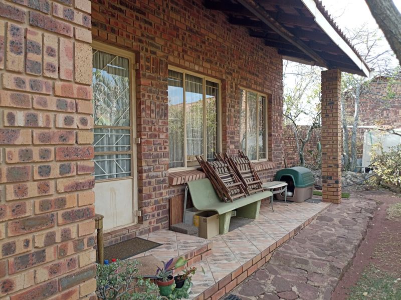 A covered patio area featuring face brick construction, tiled flooring, and brick support pillars, providing a functional outdoor space for the small holding.
