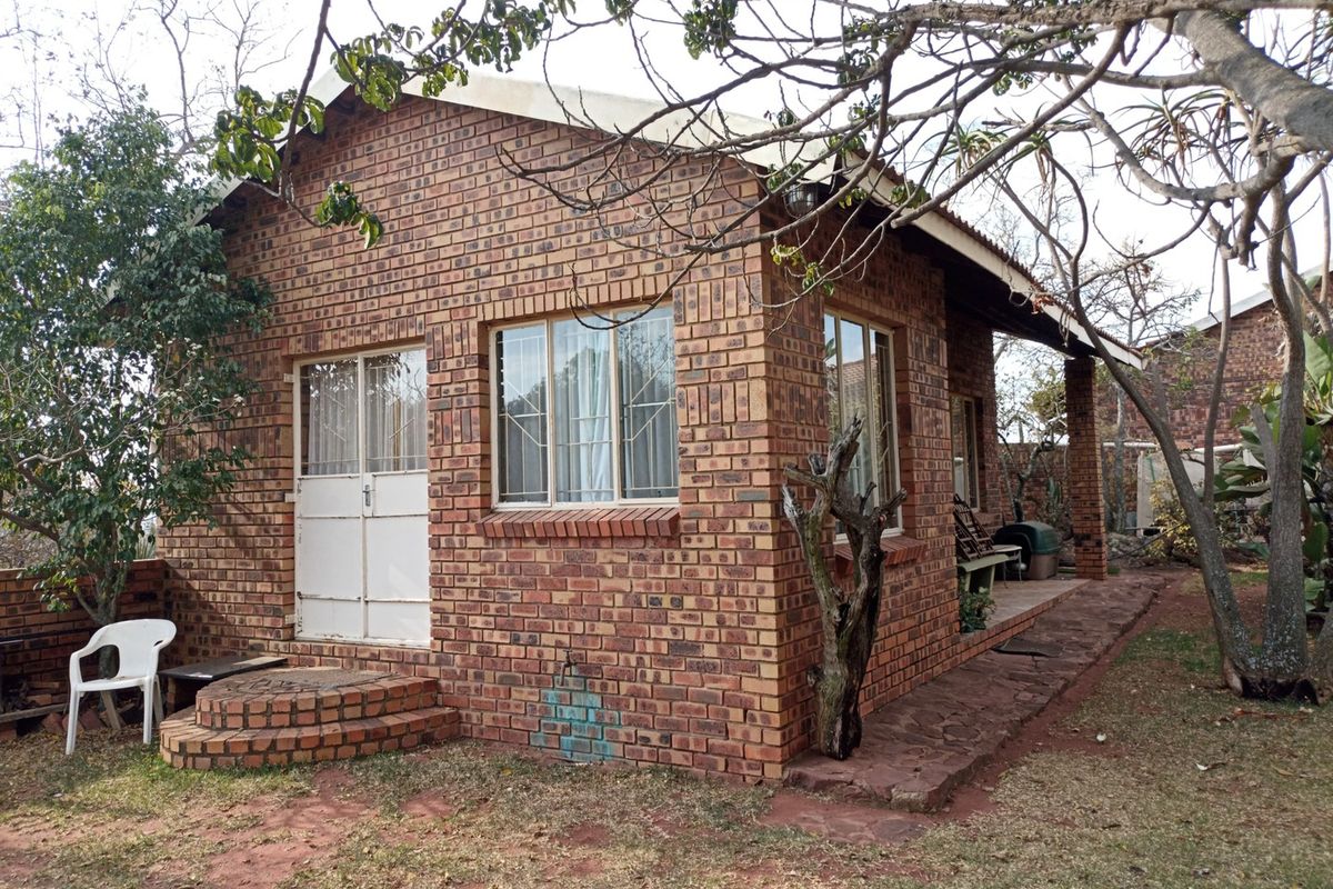 A detached face brick building featuring a covered patio, brick steps, and secure entrance, set within a garden environment.