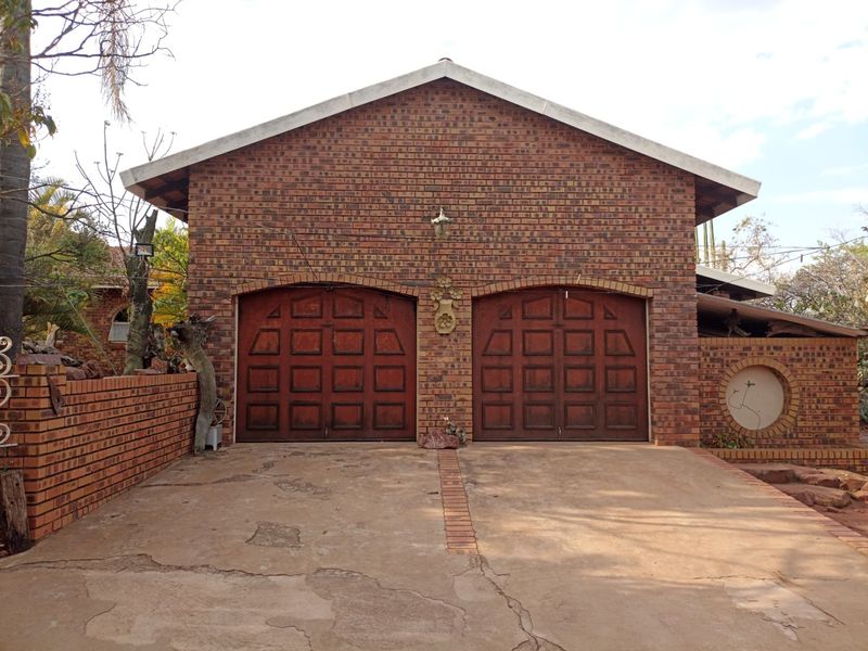A double garage featuring face brick construction and wooden garage doors, situated at the end of a concrete driveway.