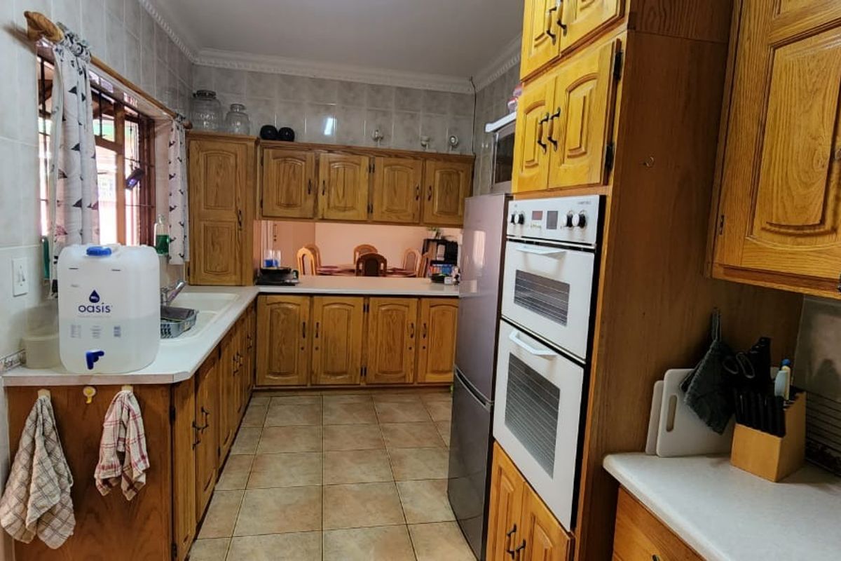 A functional kitchen featuring traditional timber cabinetry, built-in double ovens, tiled splashbacks, and tiled flooring, offering a classic layout with ample storage space.