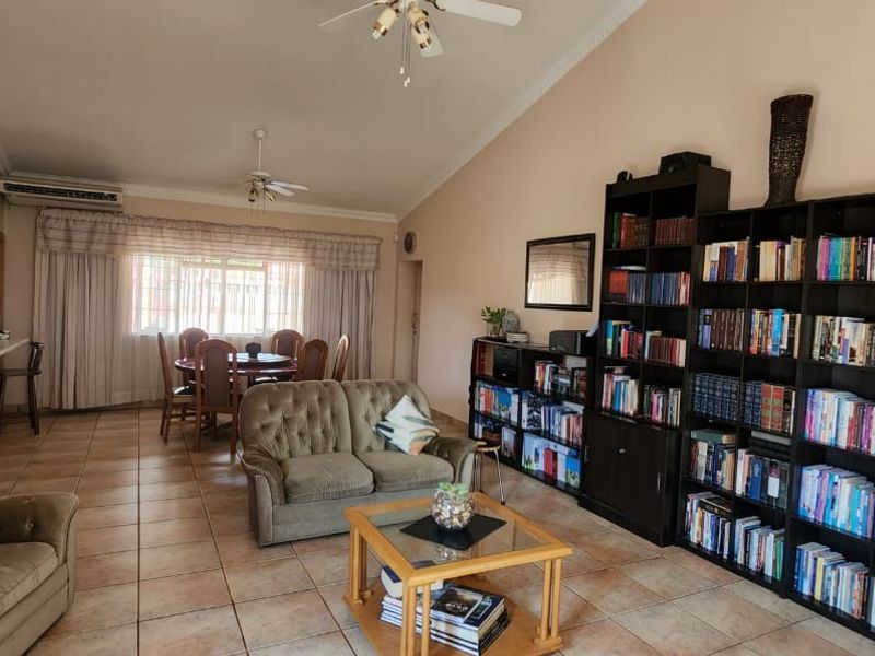 Spacious open-plan living and dining area featuring vaulted ceilings, tiled flooring, and a wall-mounted air conditioning unit.