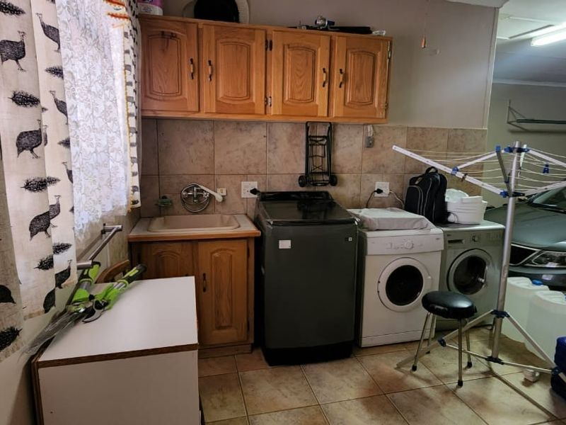A functional laundry area integrated within the garage space, featuring built-in wooden cabinetry, a utility sink, and plumbing connections for laundry appliances.
