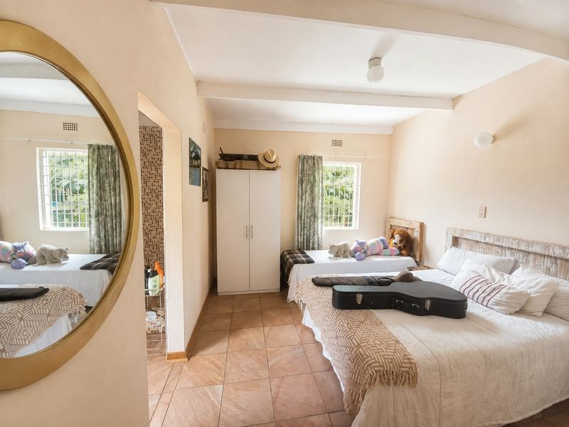 A bedroom featuring tiled flooring, exposed ceiling beams, and a built-in wardrobe, with security bars installed on the windows.