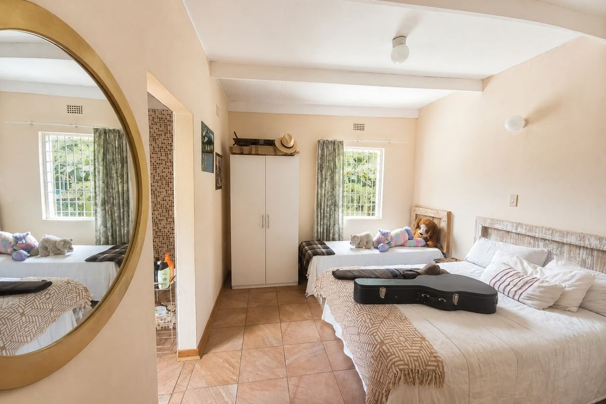 A bedroom featuring tiled flooring, exposed ceiling beams, and a built-in wardrobe, with security bars installed on the windows.