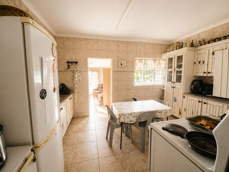 A functional kitchen featuring tiled walls and flooring with traditional built-in cabinetry, offering a dated aesthetic that could be updated with modern finishes.