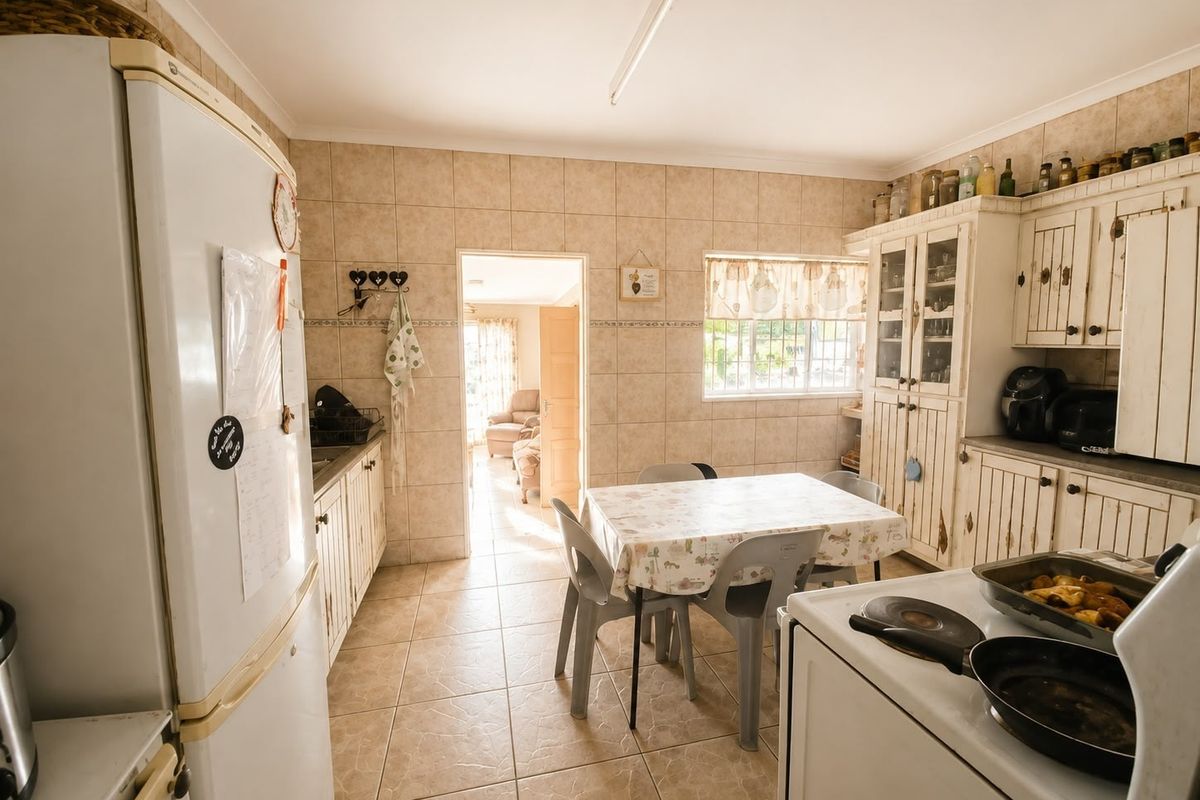 A functional kitchen featuring tiled walls and flooring with traditional built-in cabinetry, offering a dated aesthetic that could be updated with modern finishes.