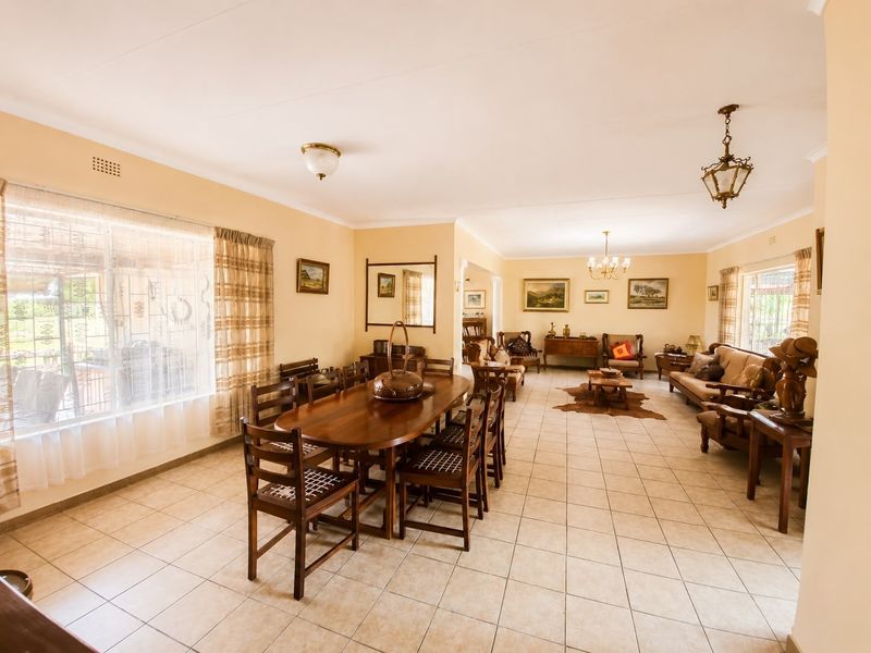 Spacious open-plan living and dining area featuring neutral wall tones, ceramic tiled flooring, and ample natural light from large windows.