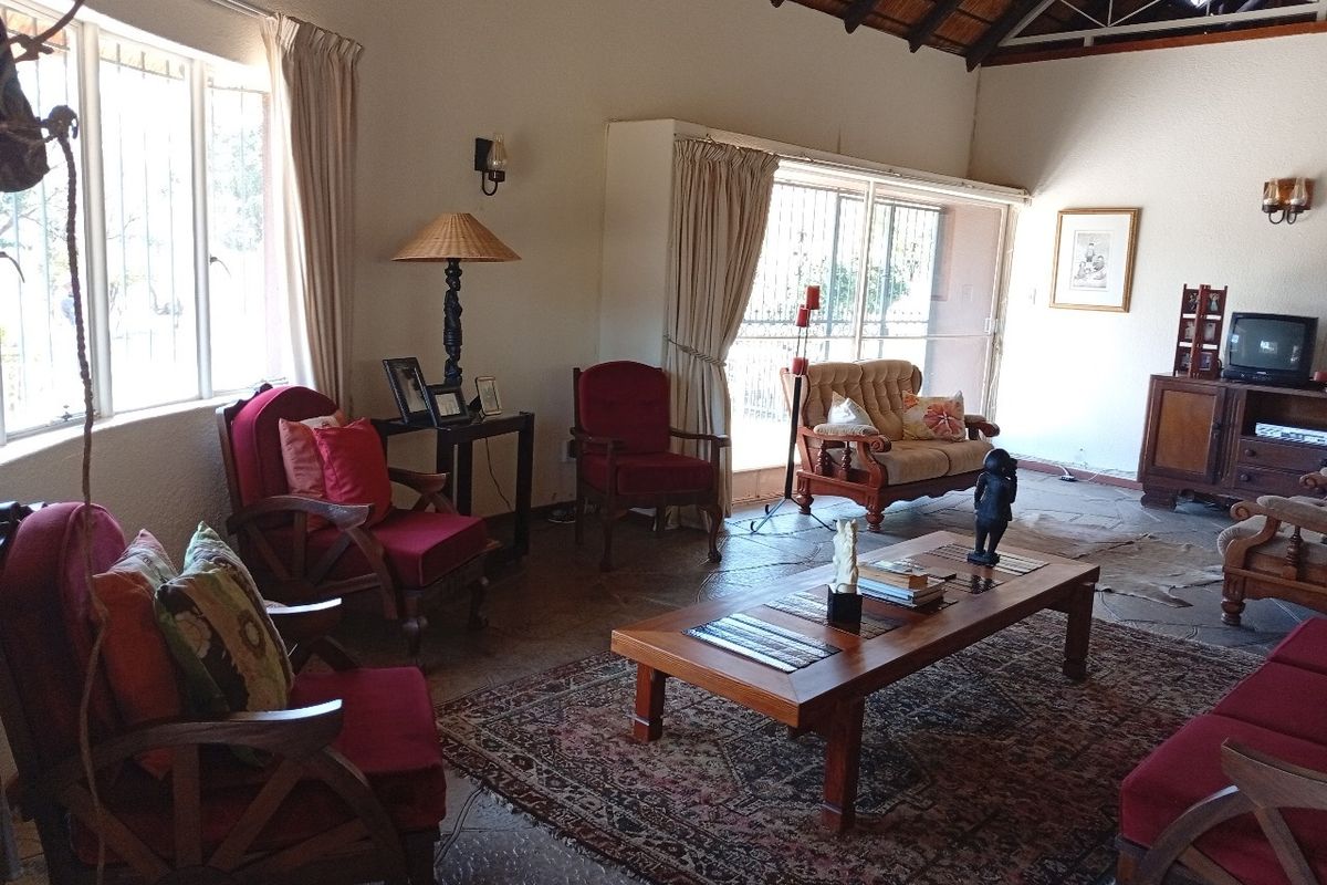 Spacious living room featuring exposed timber roof trusses, a thatched ceiling, and natural stone flooring with large sliding doors leading to the exterior.