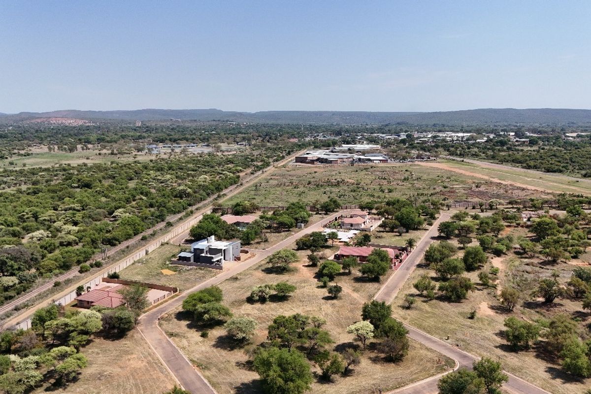 An aerial view of a residential development area featuring paved roads, established plots, and surrounding natural landscape.