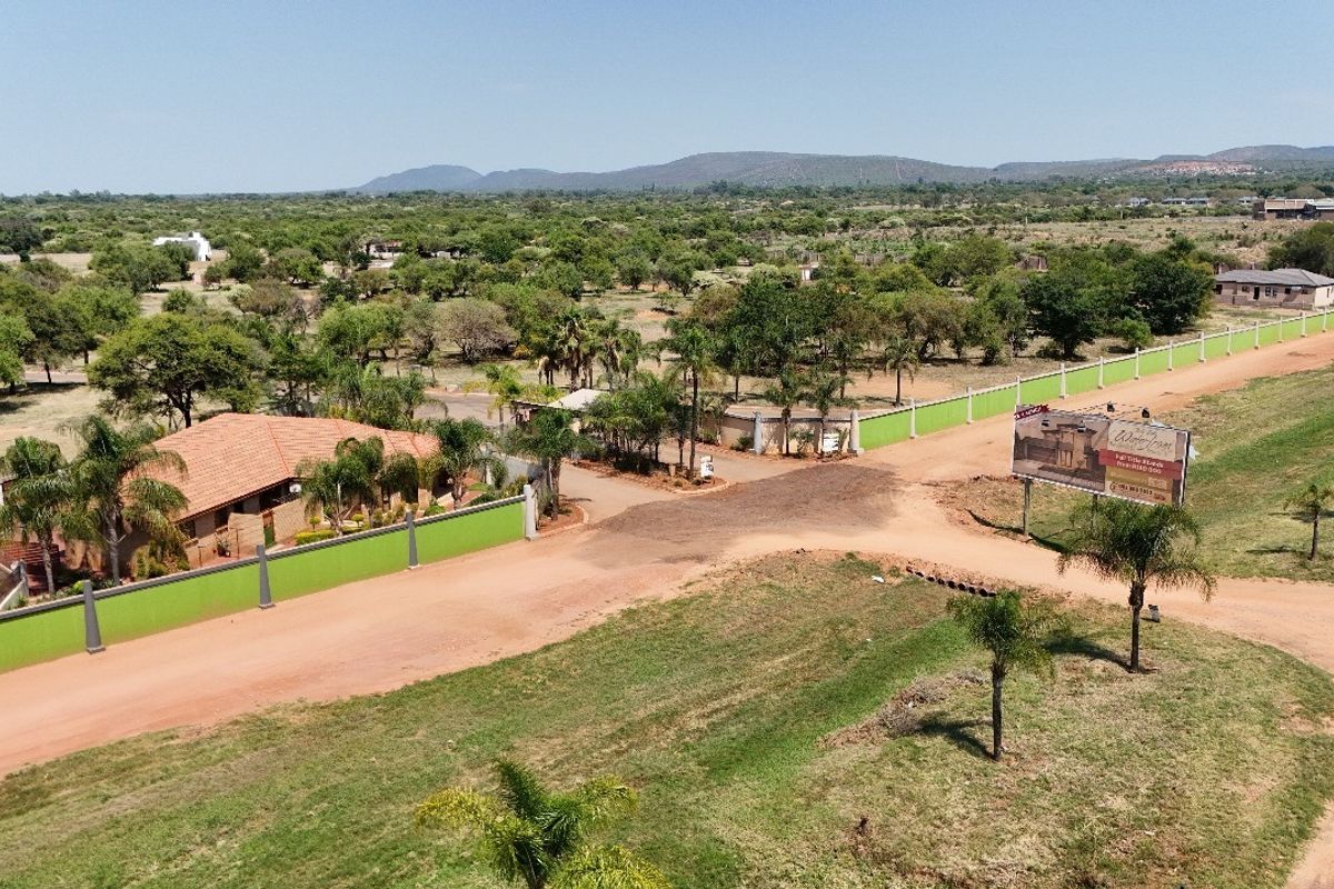 Aerial view of a residential land development featuring perimeter walls, dirt access roads, and surrounding natural landscape.