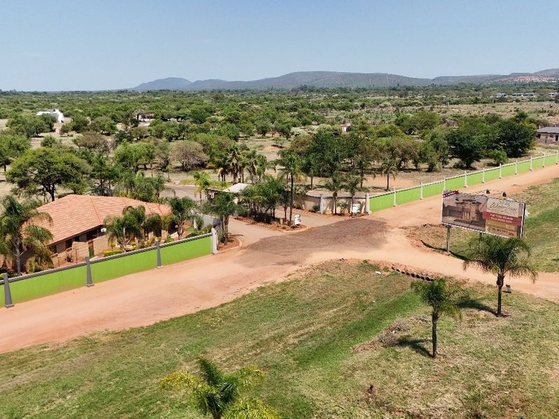 Aerial view of a residential land development featuring perimeter walls, dirt access roads, and surrounding natural landscape.