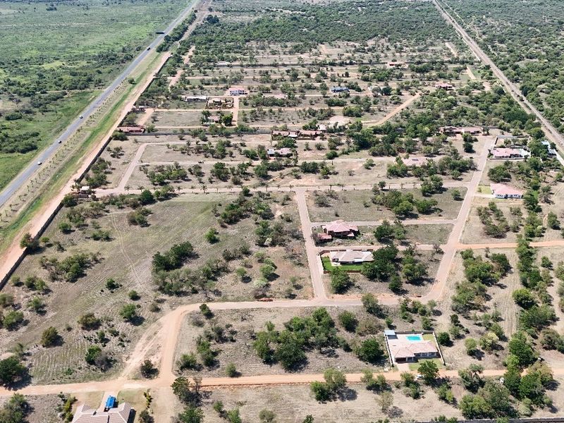 An aerial view of a residential estate development featuring multiple plots, established road infrastructure, and surrounding natural landscape.