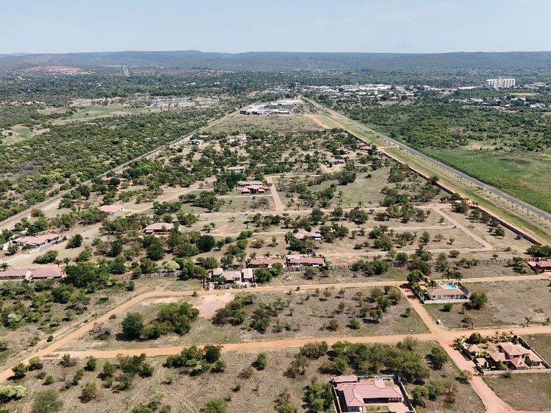 Aerial view of a residential estate development featuring multiple plots, unpaved access roads, and established vegetation in a semi-rural setting.