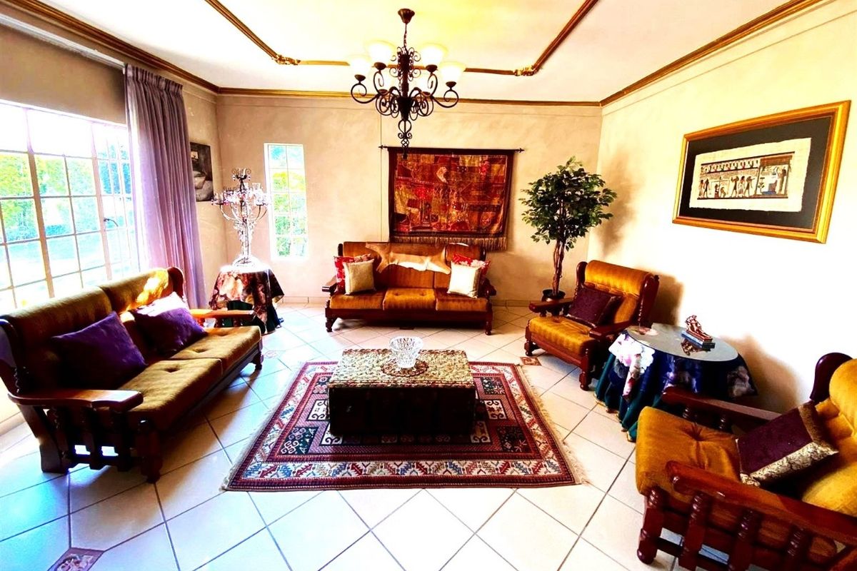A spacious living room featuring tiled flooring, decorative ceiling coving, and large windows that provide ample natural light.