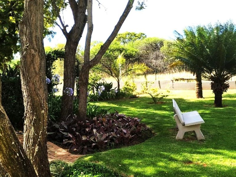 A well-maintained garden area featuring mature trees, manicured lawn, and established landscaping, providing a peaceful outdoor space on the small holding.