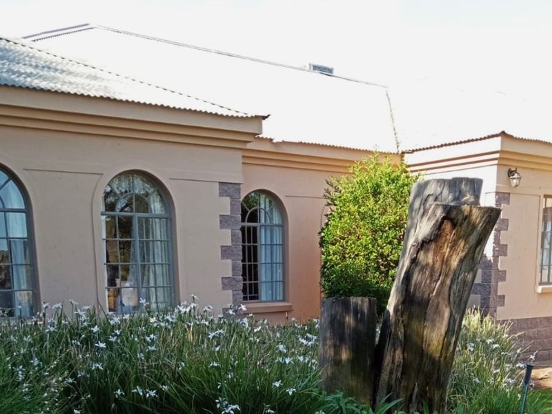 A view of the exterior rear facade featuring arched windows, stone-accented corners, and a corrugated metal roof.