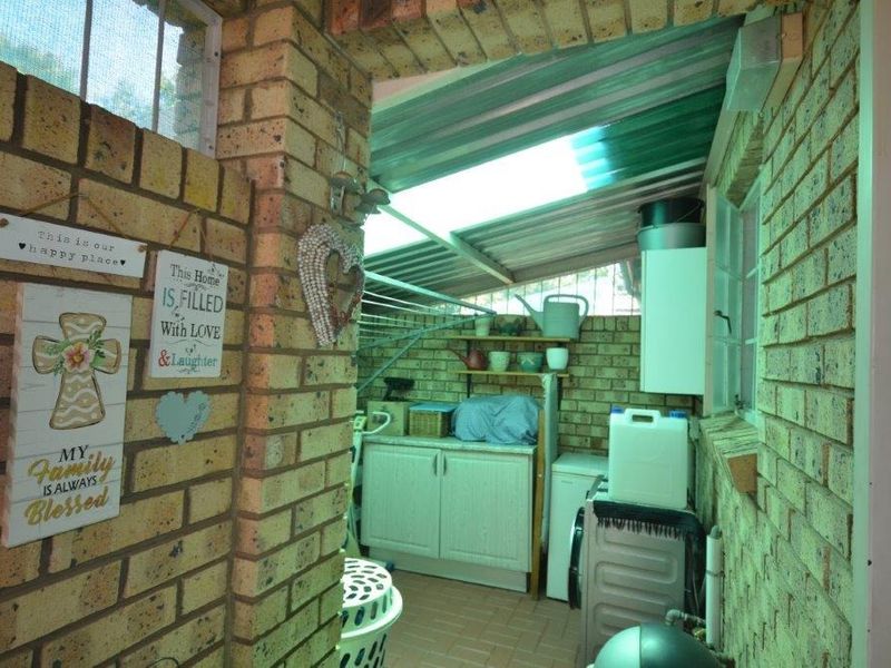 A functional utility or laundry area featuring exposed brick walls, built-in cabinetry, and a translucent roof providing natural light.