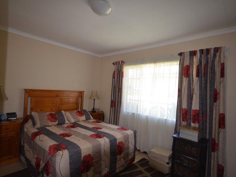 A functional bedroom featuring tiled flooring and a window with curtain tracks, offering a neutral base for personalization.