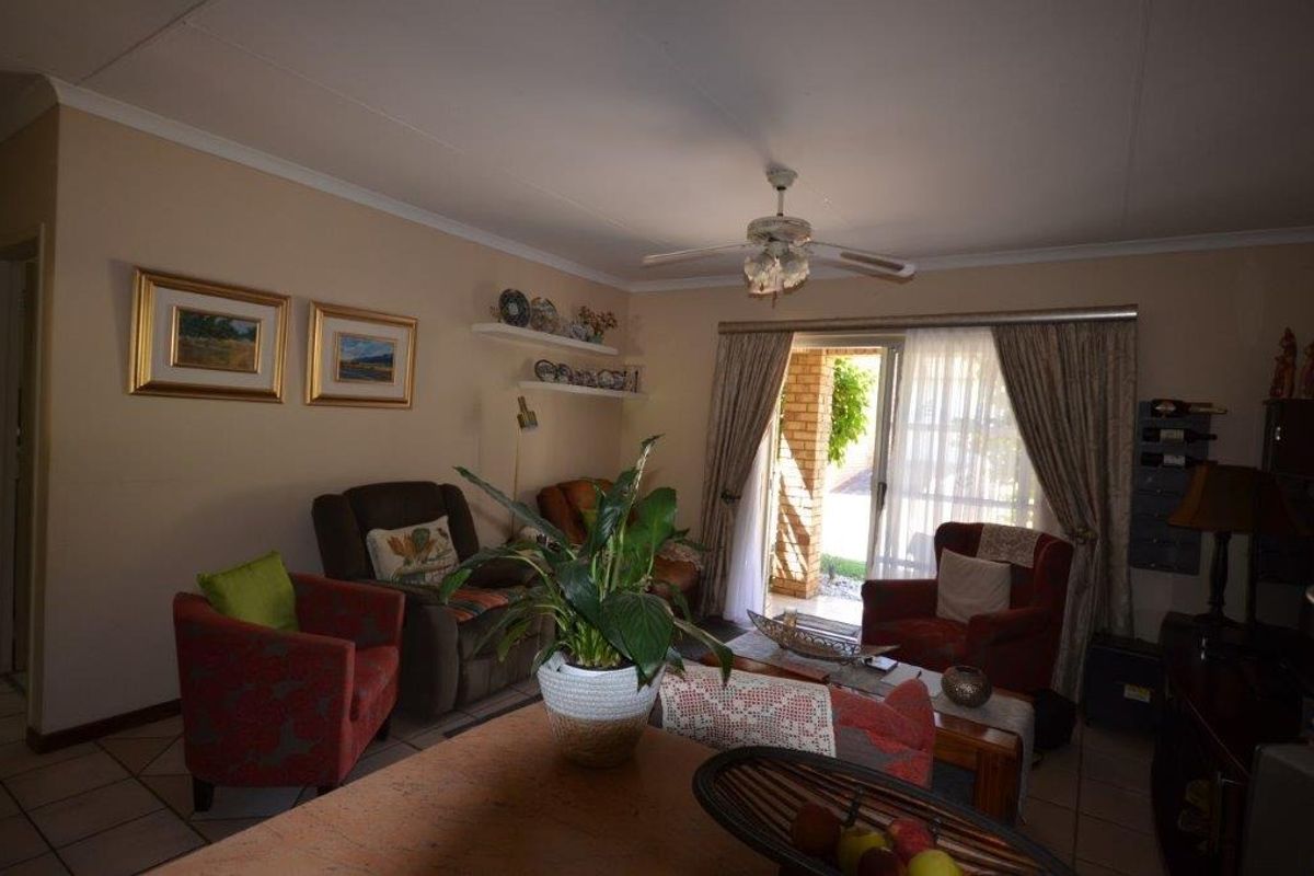 A comfortable living room featuring tiled flooring, a ceiling fan, and a sliding glass door providing access to the outdoor area.