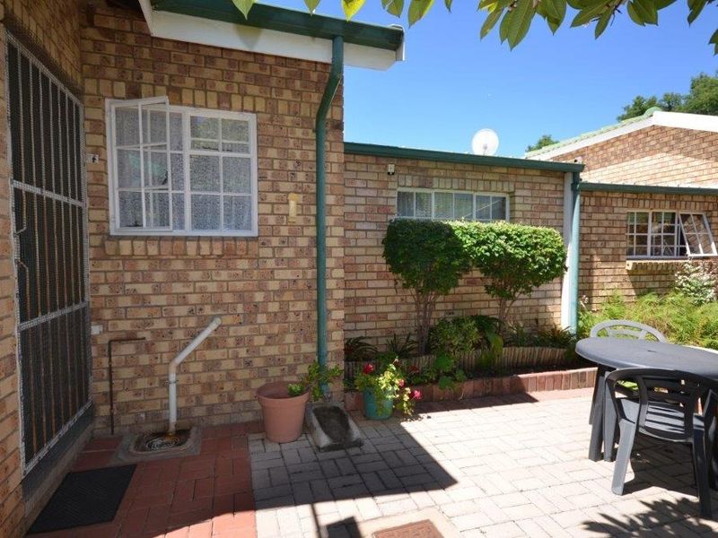 A paved outdoor patio area featuring face brick walls, guttering, and security-fitted windows, providing a functional space for outdoor relaxation.