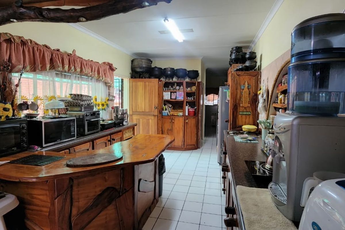 A rustic-style kitchen featuring extensive wooden cabinetry, a custom wooden breakfast bar, and tiled flooring, offering a traditional and functional workspace.