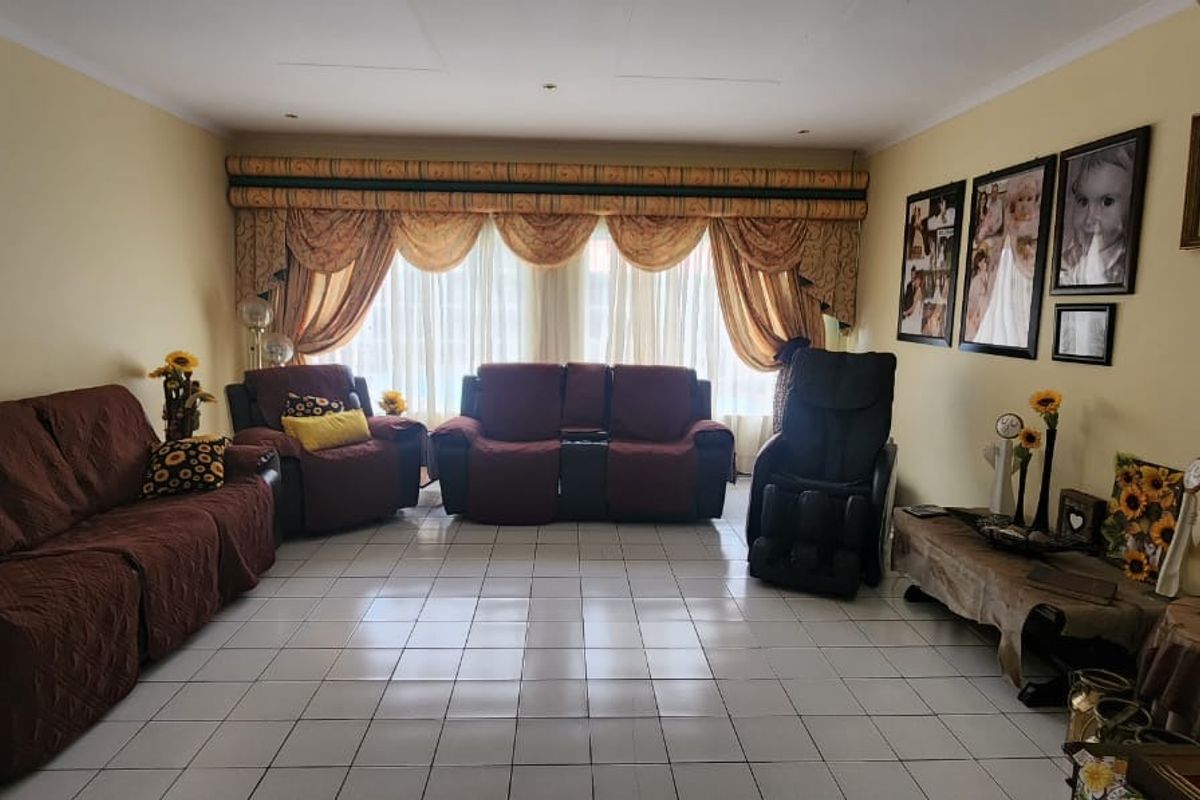 A spacious living room featuring tiled flooring, recessed ceiling lighting, and a distinctive arched entryway, offering a comfortable and functional living space.