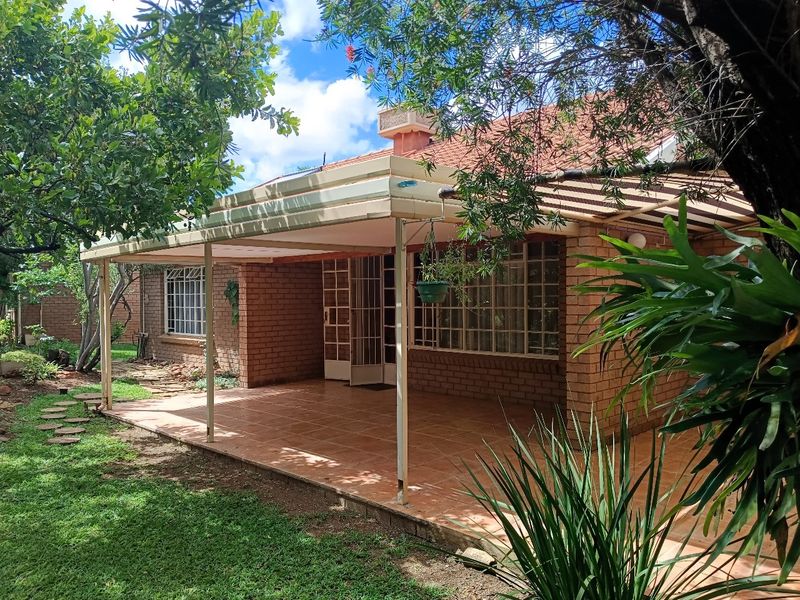 A spacious covered patio with tiled flooring, brick exterior walls, and direct access to the garden, offering a pleasant outdoor living space.