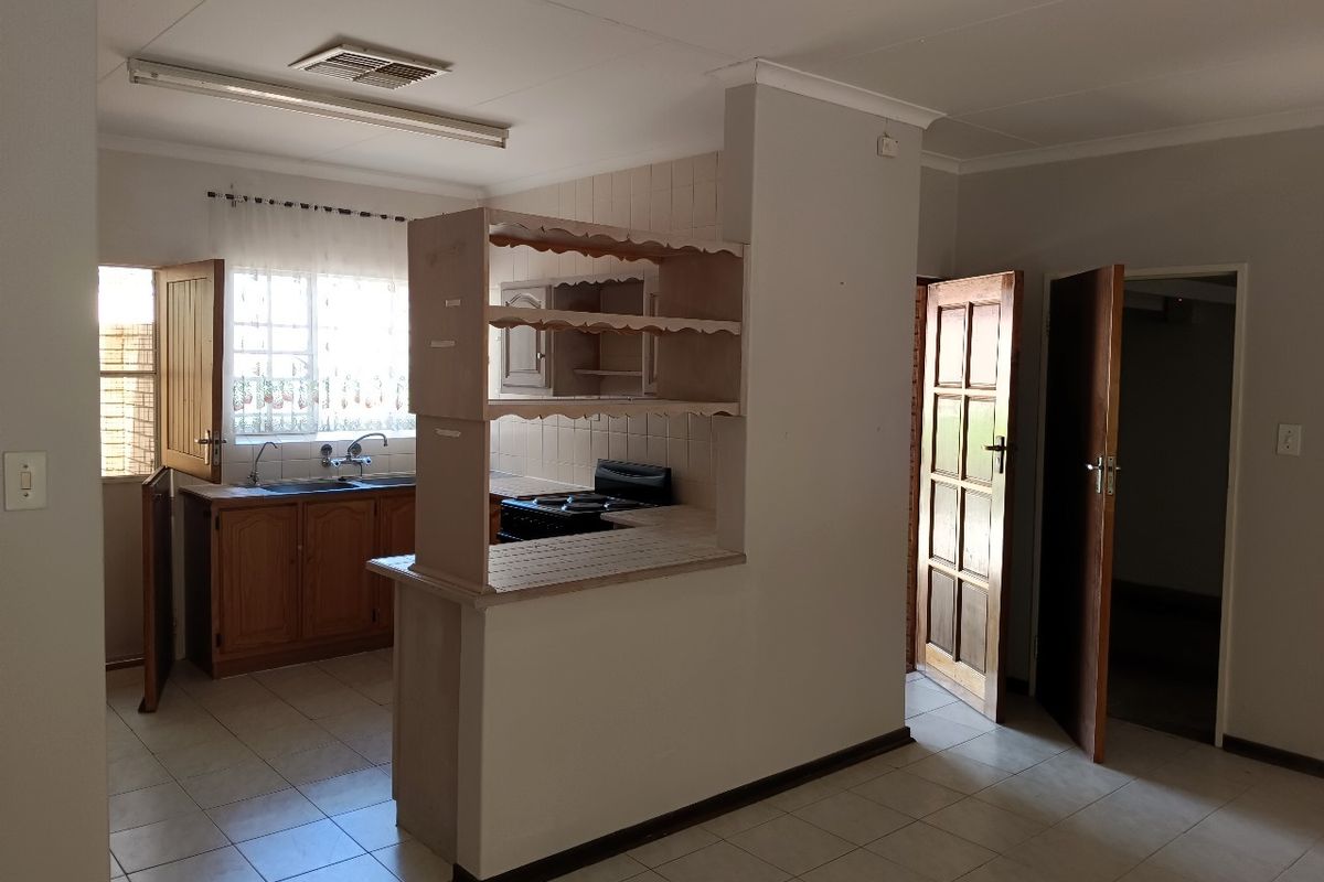 A functional kitchen area featuring built-in timber cabinetry, tiled splashbacks, and tiled flooring, offering a clean, blank canvas for potential modern updates.