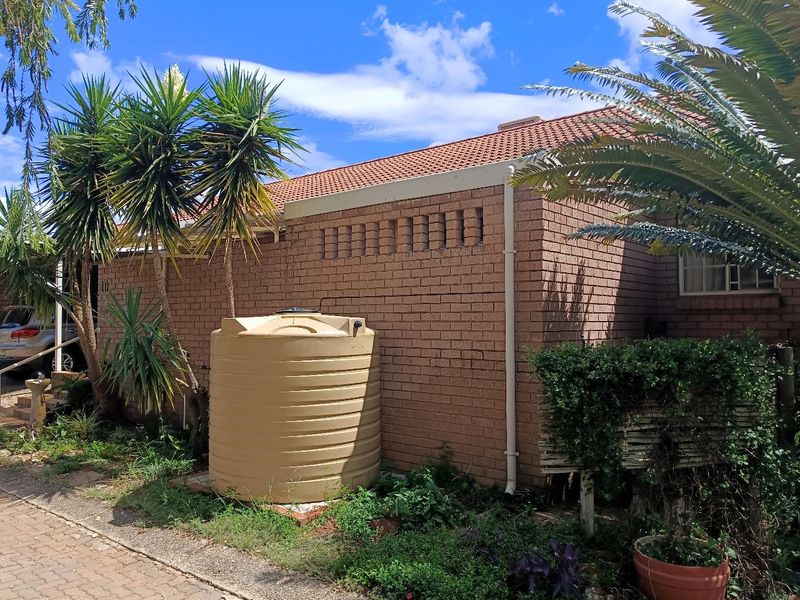 Rear exterior view of the retirement unit featuring face brick walls, a tiled roof, and a large water storage tank.