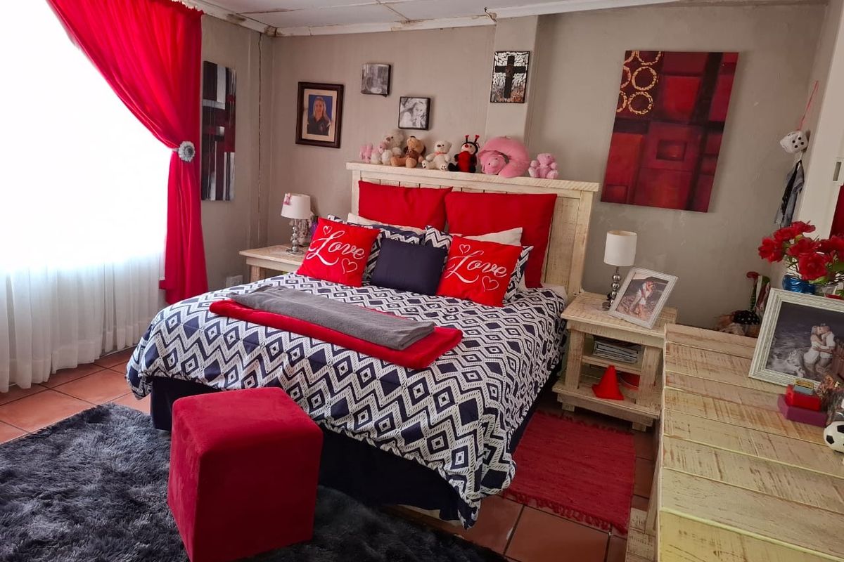 A bedroom featuring tiled flooring and ceiling tiles, currently showing signs of wear including damaged ceiling panels and wall cracks.