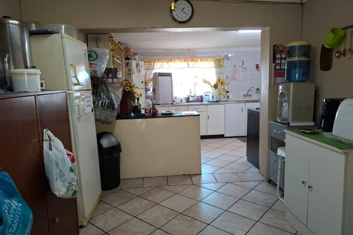 A functional kitchen area featuring tiled flooring, built-in cabinetry, and a central prep counter, requiring cosmetic updates to modernize the space.