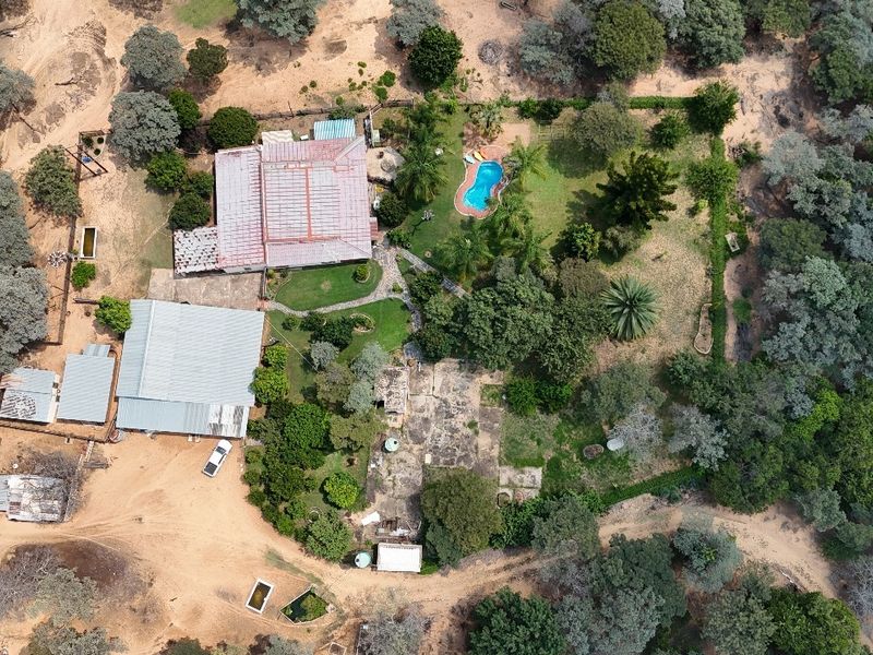 Aerial view of the small holding property featuring multiple outbuildings, a swimming pool, and extensive landscaped grounds with mature trees.