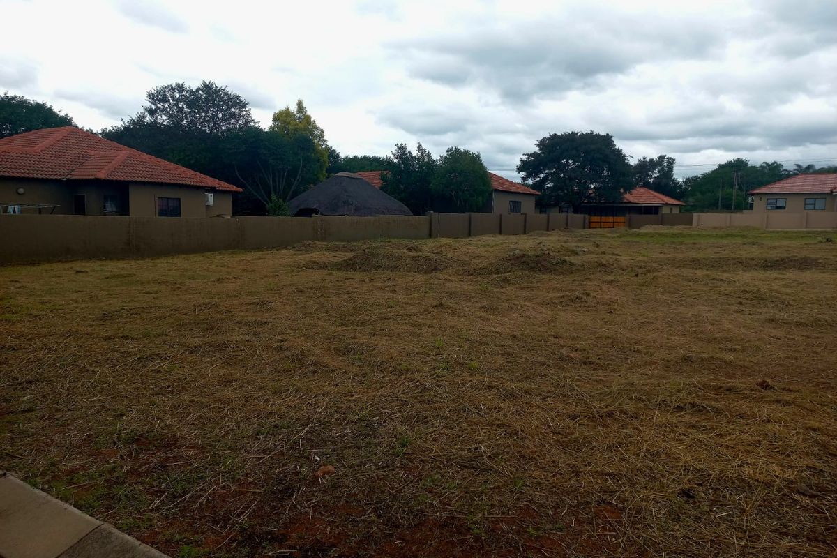 A view of a vacant residential plot featuring a perimeter wall and cleared ground, suitable for new development.