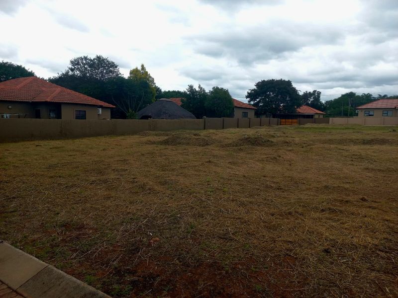 A view of a vacant residential plot featuring a perimeter wall and cleared ground, suitable for new development.