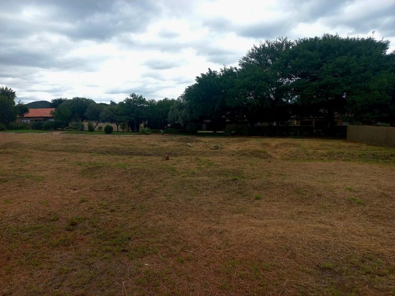A view of a vacant residential plot featuring established trees and natural grass cover, suitable for future development.