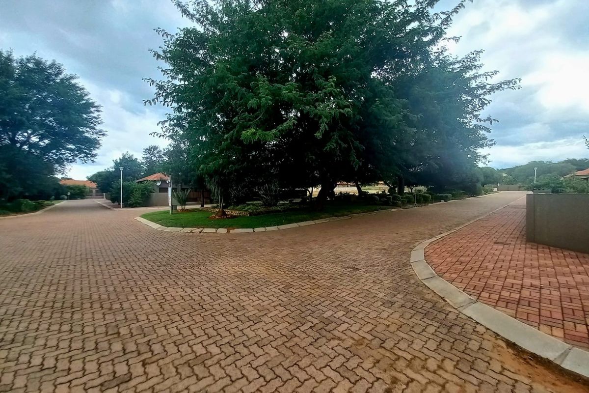 A view of a paved residential street featuring mature trees and well-maintained landscaping within a residential estate.
