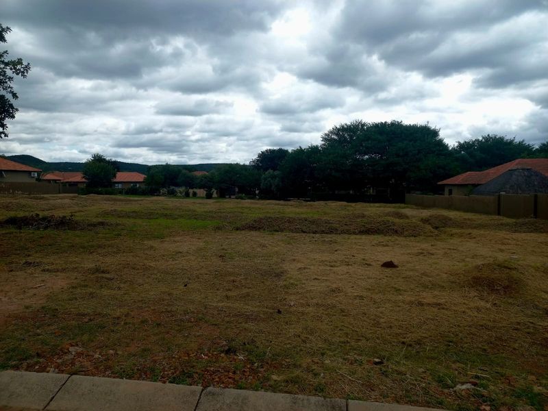 A view of a vacant residential plot featuring cleared grass and surrounding boundary walls in a residential estate setting.