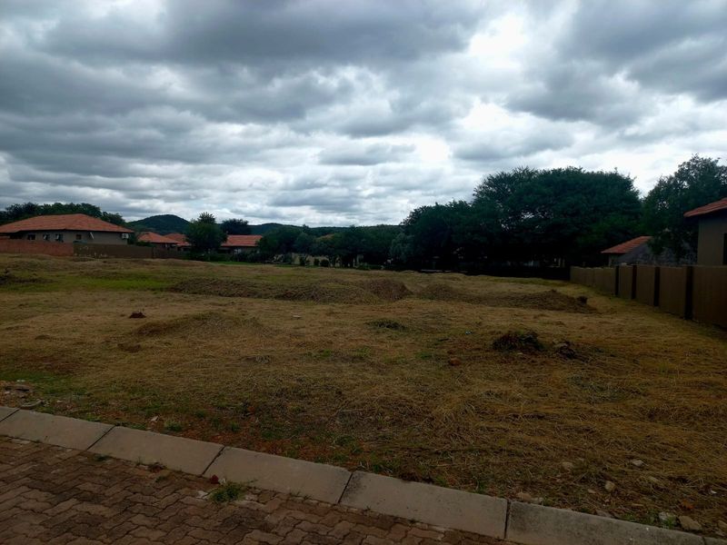 A vacant residential plot featuring a paved curb and boundary wall, offering a clear space for future development in a residential estate.