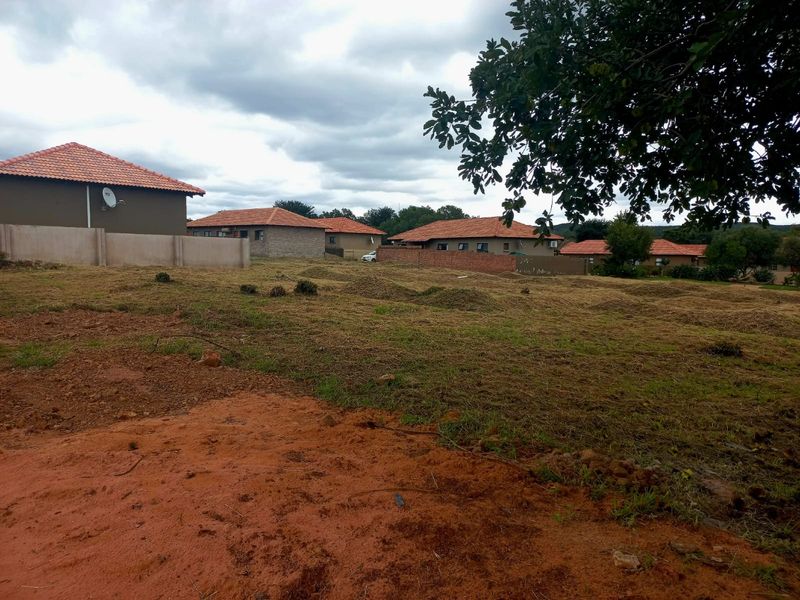 A vacant residential plot of land featuring cleared grass and boundary walls, situated in a developed neighborhood setting.