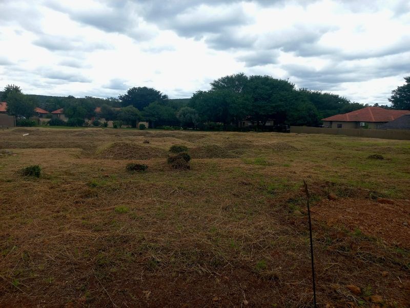 A vacant residential plot featuring cleared land and perimeter boundary walls, situated in a developed neighborhood setting.