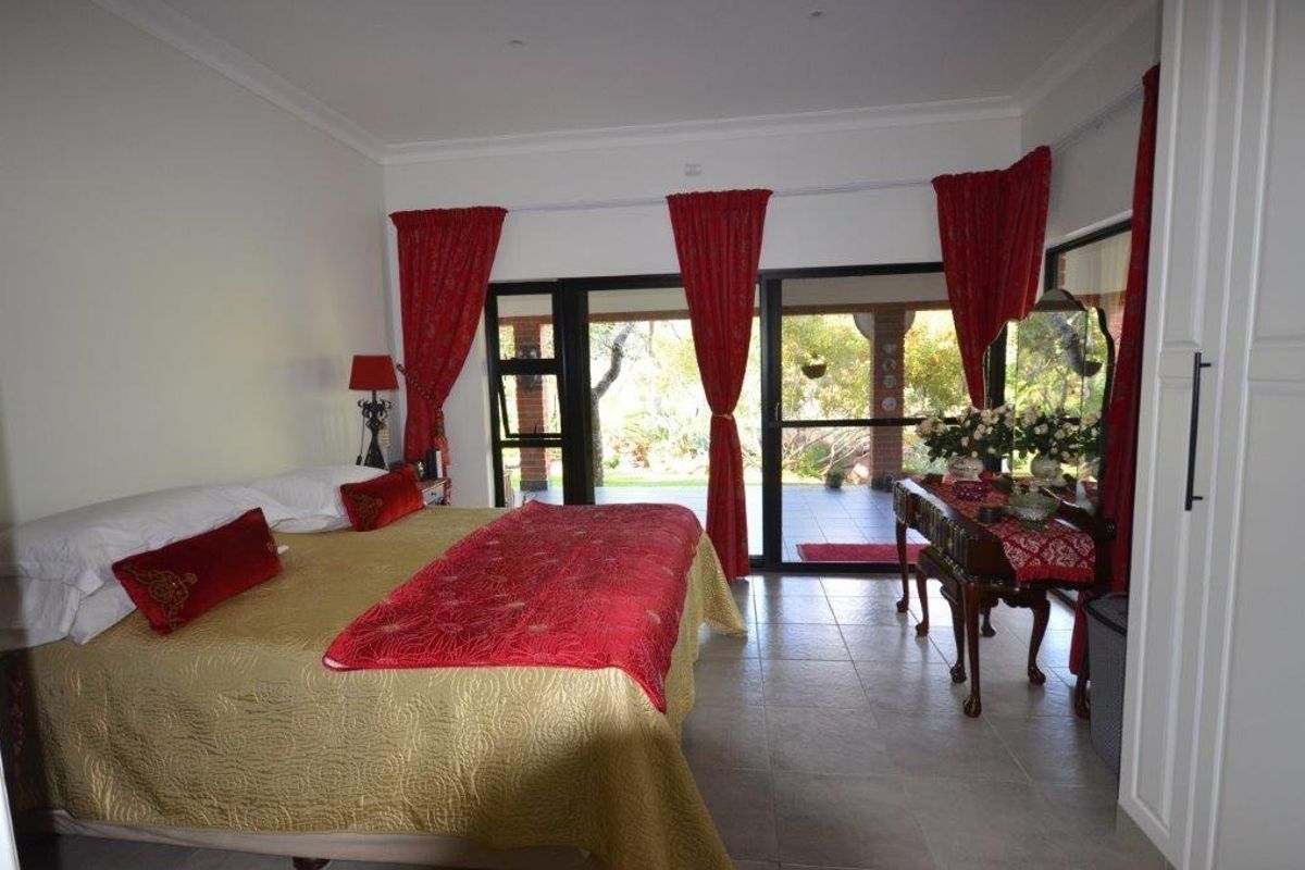 Spacious bedroom featuring tiled flooring, built-in cupboards, and large sliding glass doors providing direct access to the outdoor patio area.