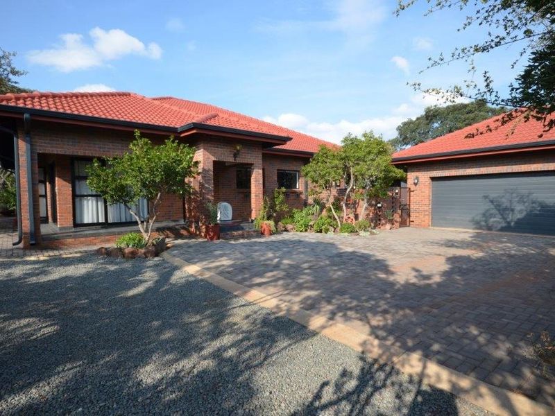 A well-maintained single-story brick house featuring a tiled roof, paved driveway, and an integrated double garage with a covered entrance.