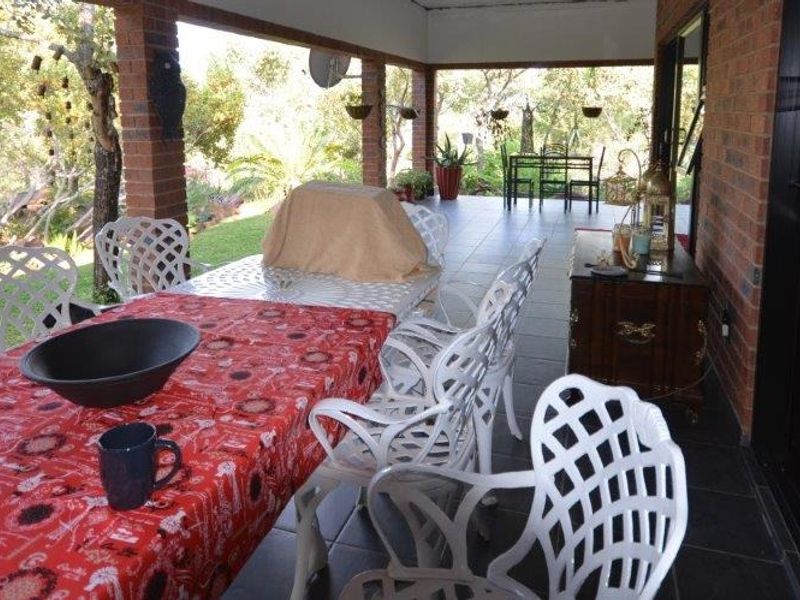 A spacious covered patio featuring exposed brick pillars and tiled flooring, offering a seamless transition to the garden area.