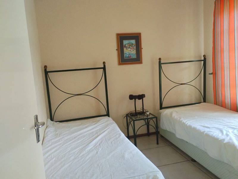A bedroom featuring tiled flooring and neutral wall finishes, currently configured with twin beds.