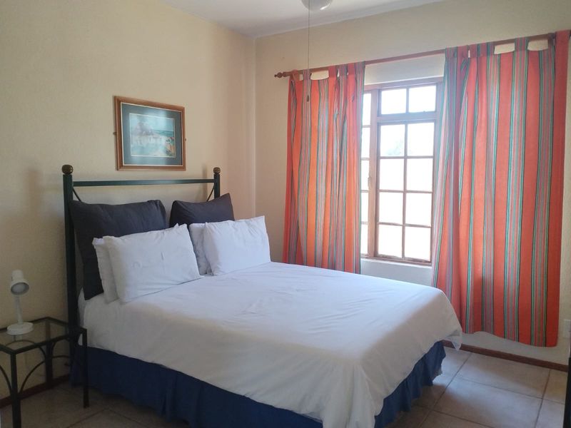 A bedroom featuring tiled flooring, a timber-framed window, and a ceiling fan, offering a functional and comfortable living space.