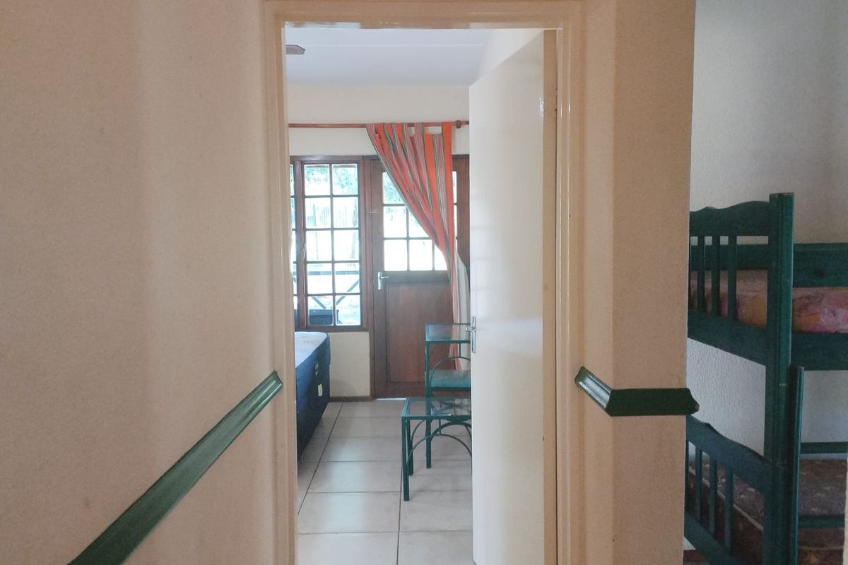 A view through a doorway into a bedroom, featuring tiled flooring and traditional wooden door frames with decorative chair rail molding.