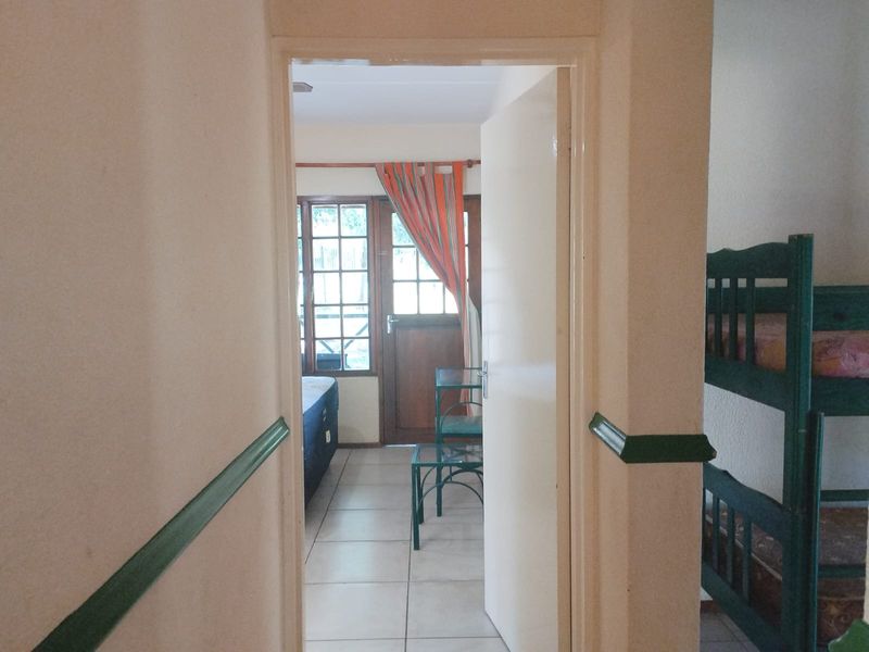 A view through a doorway into a bedroom, featuring tiled flooring and traditional wooden door frames with decorative chair rail molding.