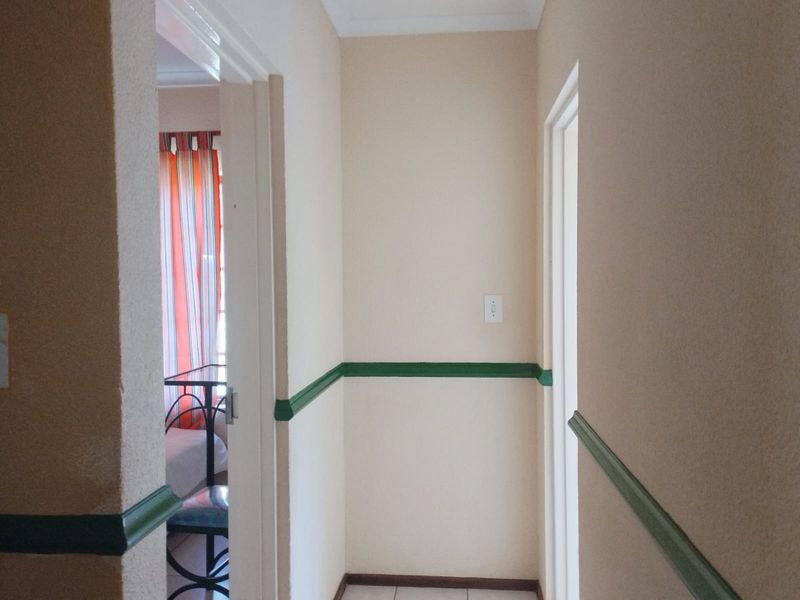 A simple interior hallway featuring tiled flooring and decorative chair rail molding along the walls.