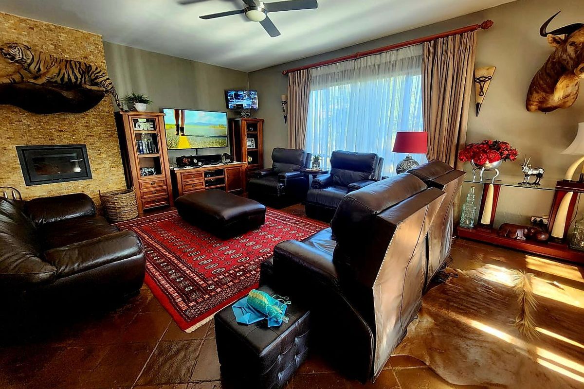 Spacious living room featuring a built-in fireplace with stone cladding, ceiling fan, and tiled flooring, offering a comfortable and inviting atmosphere.